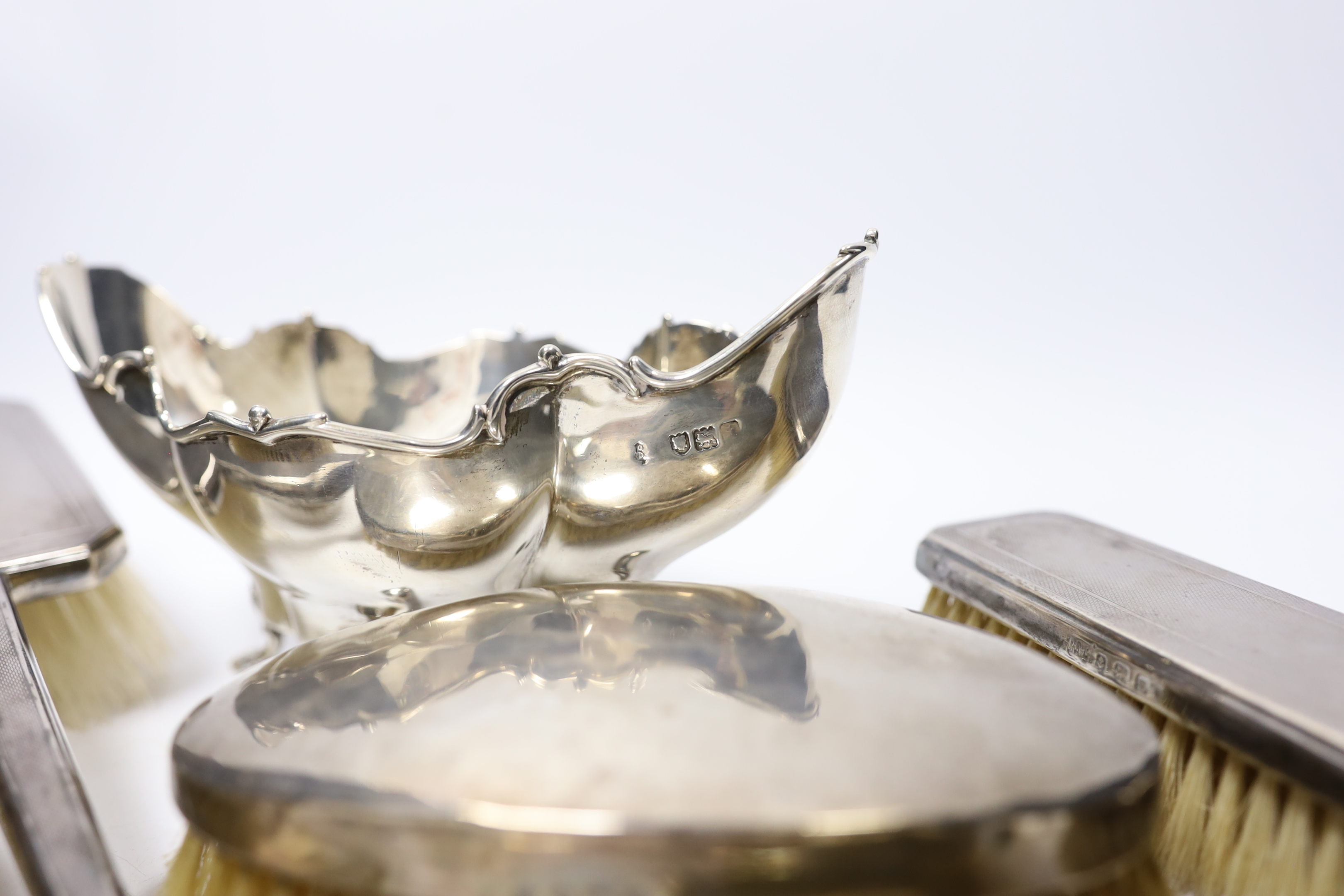 A George III silver Old English pattern basting spoon, with base marks, date letter rubbed, an Edwardian silver bowl and four silver mounted brushes.